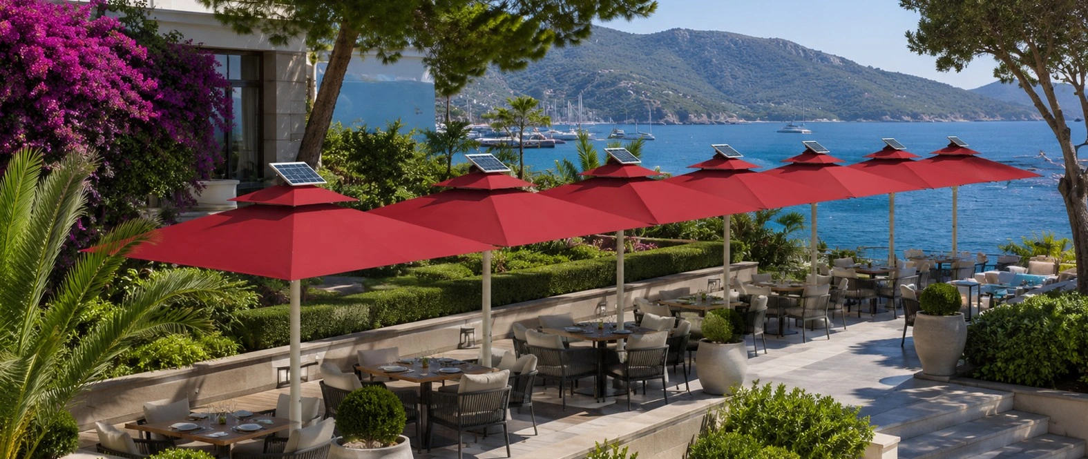 Deniz Manzaralı Otel İçin Solar Panelli Şemsiye Uygulaması | Polo Şemsiye Deniz manzaralı otel terasında kırmızı kumaşlı solar panelli şemsiyeler